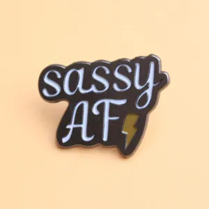 Close-up detail of a trendy metal enamel lapel pin featuring sassy letters and lightning bolt.