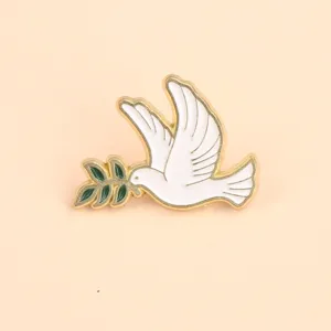 Enamel peace dove brooch detail, golden outline with green olive branch, exquisite clothing accessory.