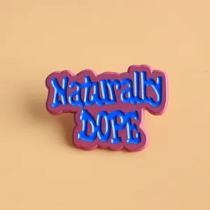 Dettaglio ravvicinato della spilla smaltata con slogan inglese colorato, ottima.