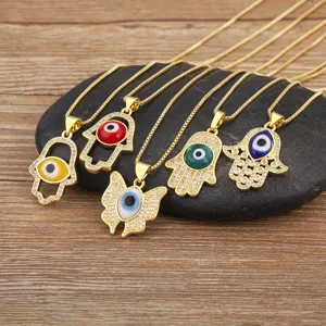 Detailed view of micro-pave zirconia evil eye and hamsa hand butterfly necklaces on dark stone.