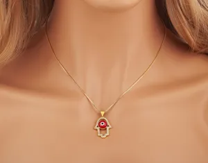 Gold plated Hamsa hand necklace featuring red evil eye pendant and micro-set cubic zirconia.