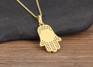 Close-up detail of the gold-plated Hamsa hand pendant featuring intricate back texturing.