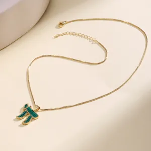 Close-up detail shot of a gold box chain necklace featuring a green stone Hebrew Chai pendant.