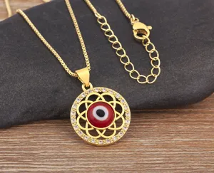 Close-up detail of golden evil eye pendant necklace with red zircon and crystal stones.