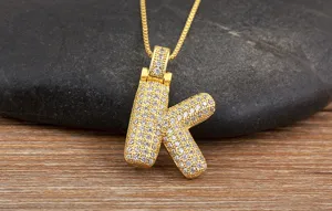 Gros plan détaillé d'un collier pendentif lettre K en zircon doré sur un beau fond en bois.
