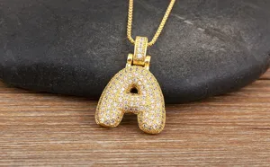 Gros plan détaillé d'un collier pendentif lettre A doré pavé de zircons étincelants.