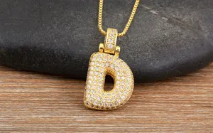 Gros plan d'un pendentif lettre D plaqué or avec des détails de zircone cubique étincelants.