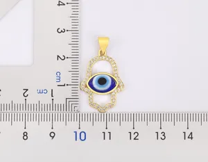 Detail shot of gold plated hamsa hand evil eye pendant with sparkling cubic zirconia stones.