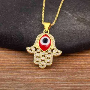 Close-up detail of gold Hamsa hand evil eye pendant necklace with micro-set cubic zirconia.