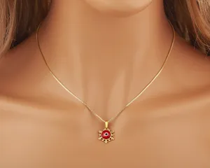 Collana con ciondolo malocchio rosso placcato oro in primo piano, dettaglio gioiello.