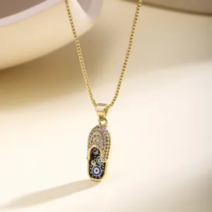 Close-up detail of gold evil eye slipper pendant necklace with sparkling zirconia stones.