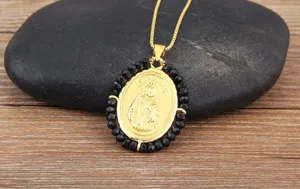 Collier pendentif San Judas plaqué or avec perles acryliques noires, gros plan de bijoux.