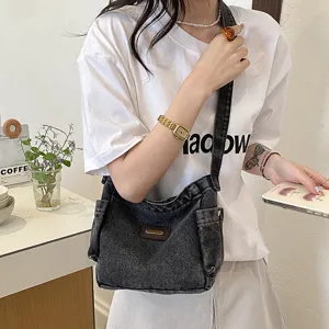 Close-up view of the casual dark denim shoulder bag showing its large capacity and front pockets.
