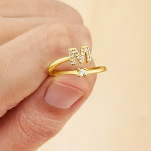 Close-up of gold initial M adjustable ring featuring shimmering paved cubic zirconia stones.
