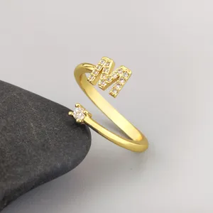 Gold plated open ring detail featuring micro-paved cubic zirconia letter M and single stone.