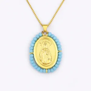 Collier pendentif ovale portrait San Judas plaqué or 18K avec perles acryliques bleues.