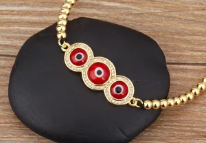 Détail en gros plan du bracelet de perles œil maléfique plaqué or 18k avec zircon rouge.