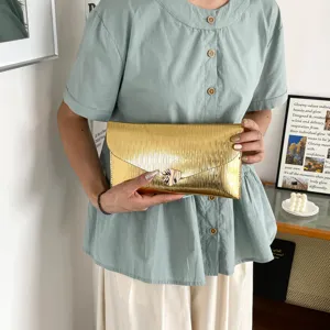 Gold metallic pleated envelope clutch bag detail, showing premium texture and elegant style.