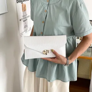Close up view of white pleated envelope clutch bag with unique metal lock clasp for women.