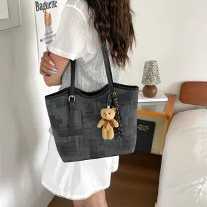 Detail shot of dark gray textured tote bag with cute bear pendant, stylish daily casual commuter bag.