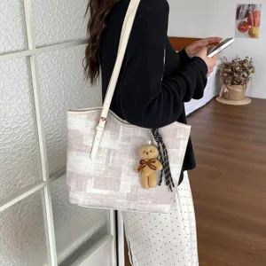 Detail of stylish casual tote bag with patchwork design and cute bear charm for daily commute.