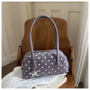 Detail view of the purple polka dot shoulder bag with a silver star charm and soft texture.