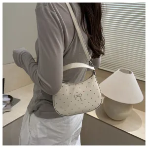 Detail shot of white patent leather shoulder bag with pink polka dots and a cute bow accent.