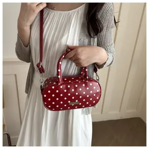 Detail van de rode schoudertas met witte polkadots, trendy handtas met handige draagriem.