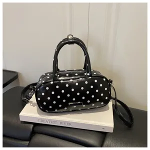 Gedetailleerd overzicht van de zwart-witte polkadot schoudertas met glanzende afwerking.