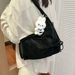 Close up detail of black slouchy shoulder bag with cute white bunny plush pendant