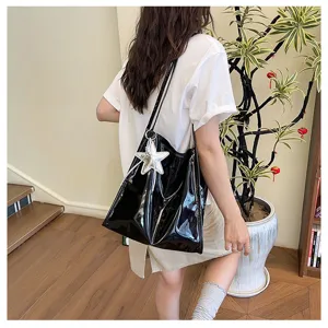 Black patent leather tote bag with silver star pendant, stylish casual commuter shoulder bag.