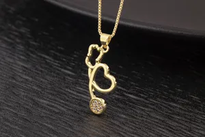 Gold stethoscope heart pendant necklace detail, sparkling cubic zirconia, elegant jewelry.