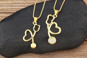 Gold plated stethoscope heart necklace detail, elegant medical jewelry pendant close up display.