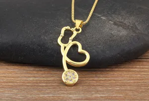 Detailed close-up of gold stethoscope heart pendant necklace, featuring sparkling crystal stones.