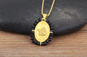 Primo piano della collana con ciondolo ad ala d'angelo ovale dorata con perline sfaccettate.