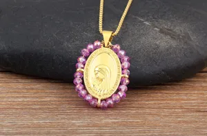 Gedetailleerd close-up van de vergulde ovale Maagd Maria hangerketting met paarse kraaltjes.