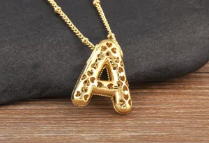 Vista dettagliata della collana con ciondolo lettera A in oro con zirconi e motivi a trifoglio.