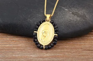 Gedetailleerde close-up van de prachtige gouden ovale hanger met stijlvolle zwarte kralen.