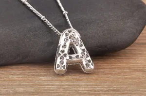 Primo piano dettagliato della collana con ciondolo lettera A in argento con zirconi e trifoglio.