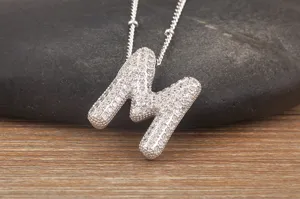 Detailed close-up of a silver-toned letter M pendant necklace, sparkling cubic zirconia pave.