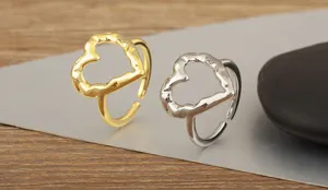 Detailansicht goldene silberne unregelmässige hohle herz verstellbare ringe auf platte.