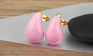 Close-up detail of candy color pink enamel teardrop earrings with gold posts for women styling.