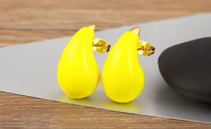 Close-up detail shot of bright yellow teardrop enamel stud earrings with gold plating finish.