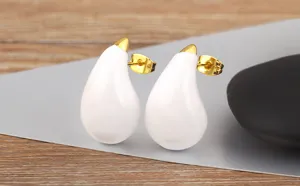 Close-up of white teardrop enamel earrings with 18k gold plated posts, candy color design.