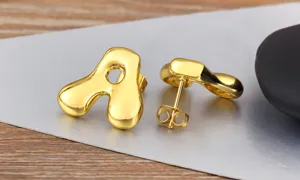 Close-up of puffy letter A gold earrings with smooth glossy finish and minimalist style.
