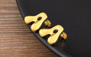 Detail view of stylish gold puffy letter stud earrings, featuring a smooth minimalist design.