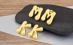 Close-up detail of stylish gold-plated puffy letter earrings featuring smooth glossy finish.