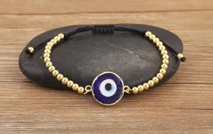Vue détaillée du bracelet de perles mauvais œil avec des perles dorées et un pendentif bleu.