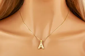 Closeup of gold-plated mother-of-pearl letter A pendant necklace, elegant niche jewelry detail.
