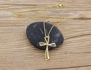 Close-up detail of a gold-plated cross pendant necklace featuring sparkling colorful cubic zirconia.